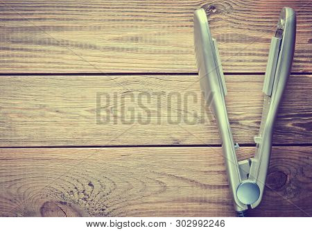 Iron For Leveling Hair On A Wooden Table. Hair Straighteners. Copy Space. Top View.