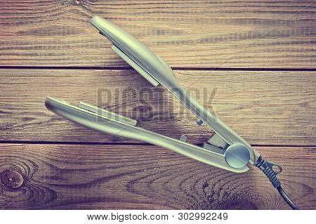 Iron For Leveling Hair On A Wooden Table. Hair Straighteners. Top View.