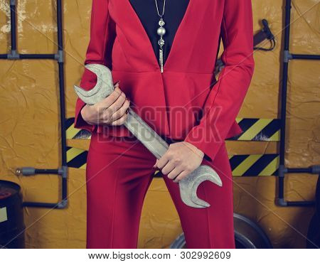Fashionable Mechanic Girl In Trendy Clothes Is Holding A Wrench On The Background Of The Workshop Of
