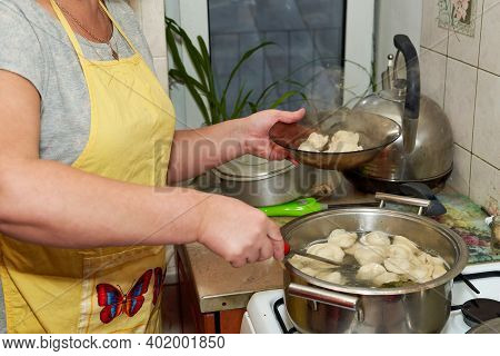 The Woman Takes Cooked Hot Dumplings From The Pan Into A Transparent Plate. Home Cooking