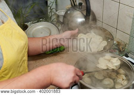 The Woman Takes Cooked Hot Dumplings From The Pan Into A Transparent Plate. Home Cooking