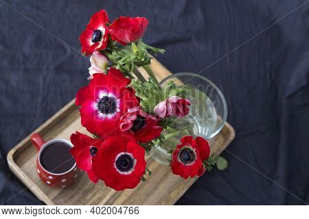 A Bouquet Of Red Anemones In A Transparent Glass Vase On A Table With A Gray Tablecloth. White Polka