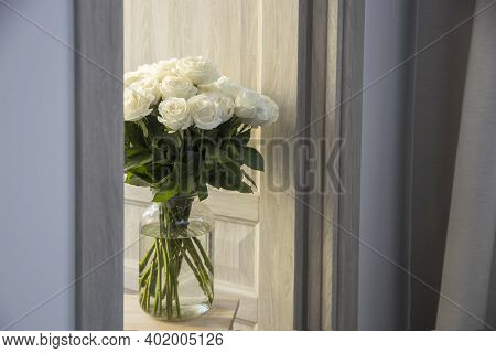 A Bouquet Of White Roses Playa Blanca. Are In Glass Vase Made Of Corrugated Glass On A High Wooden S