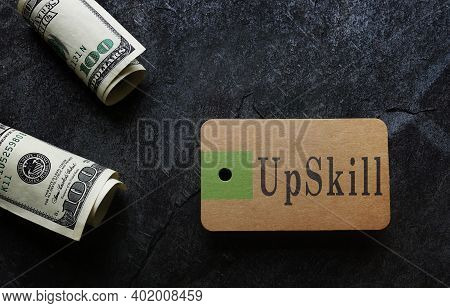 Paper Tag With Upskill Text And Hundred Dollar Bills -- Job Training Concept