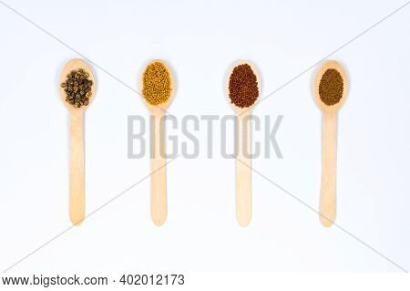 Various Seeds In Wooden Spoons On A White Background. Seeds Of Beet, Mustard, Lettuce, Arugula, On A