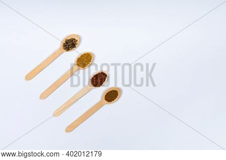 Various Seeds In Wooden Spoons On A White Background Diagonally. Seeds Of Beet, Mustard, Lettuce, Ru