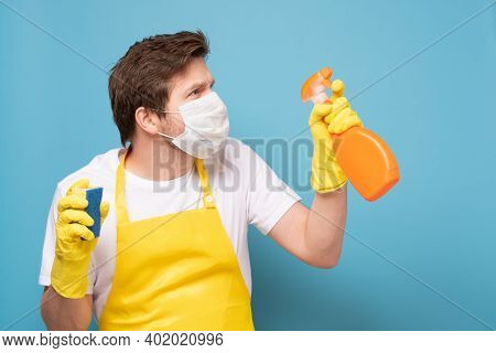 Young Seious Man In Apron, Protective Mask And Gloves Ready To Clean Everything From Coronavirus.