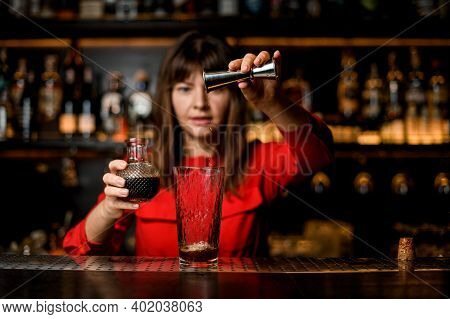 Glass Stands On Bar And Female Bartender Pours Wine From Jigger Into It