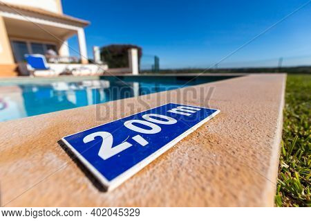 Blue Plastic Plate At The Edge Of A Swimming Pool Indicating A Depth Of 2.00 Meters