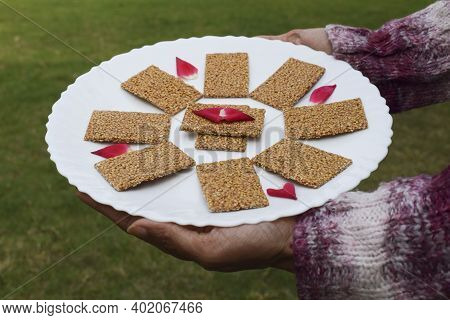Female Hand Holding Winter Special Sweet Dish Of White Sesame And Jaggery Melted In Clarified Butter