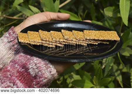 Female Hand Holding Winter Special Sweet Dish Of White Sesame And Jaggery Melted In Clarified Butter