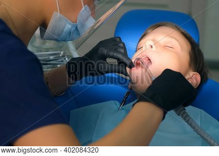 Dentist Rinses Boys Mouth Water Holding Saliva Ejector During Oral Hygienic Cleaning, Face Closeup. 