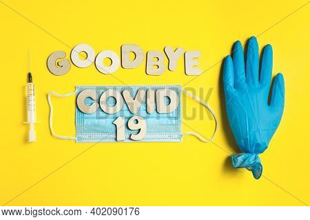 Words Goodbye Covid 19 From Wooden Letters And Syringe With Vaccine, Inflated Medical Glove Waving B