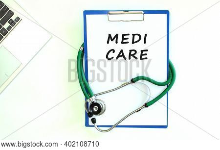 Stethoscope And Clipboard With Medi Care Text On White Sheet Of Paper And Copy Space.
