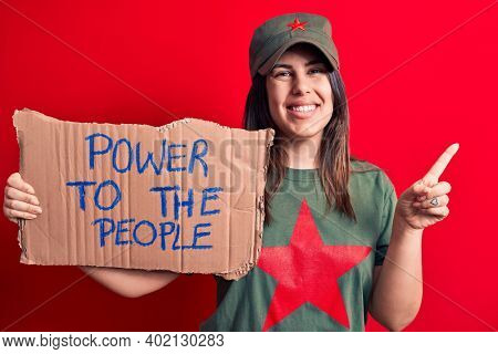 Beautiful woman wearing t-shirt with red star communist symbol asking for social movement smiling happy pointing with hand and finger to the side