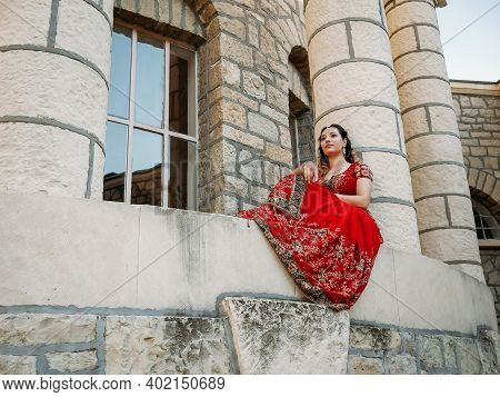 Young Beautiful Indian Woman Walks On Ancient Architecture Streets Of City Of India Dressed In Red S