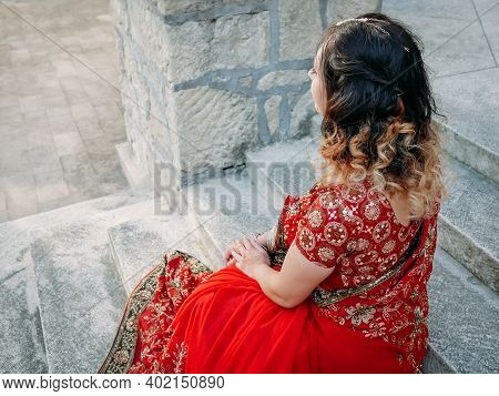 Young Beautiful Indian Woman Walks On Ancient Architecture Streets Of City Of India Dressed In Red S