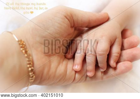 A Mother Wearing A Maman Bracelet Holding The Hand Of Her Infant.