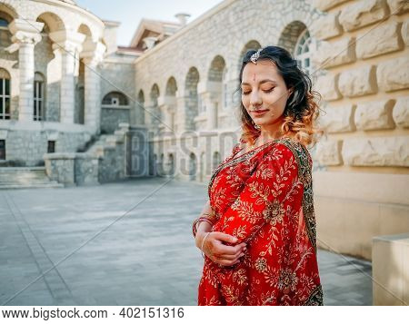 Young Beautiful Indian Woman Walks On Ancient Architecture Streets Of City Of India Dressed In Red S