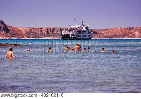 Crete Or Kreta, Greece - September 15, 2017: Tourists Swimming Against Ship Cruise Docked In Balos L