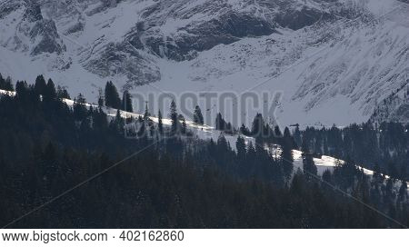 Snow Covered Mountain Ridge, Pine Forest And Cliff In Gsteig Bei Gstaad.