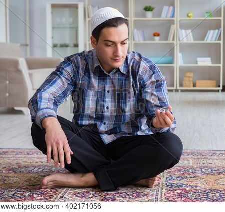 Young muslim man praying at home