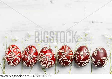 Row Of Red And White Handmade Wax Dyed Easter Eggs. Ukrainian Pysanka Frame On White Wooden Backgrou