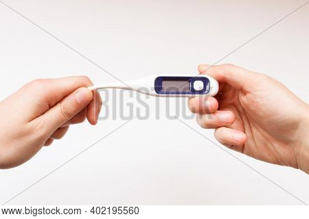 A Boy Hands Holding A Digital Thermometer. Health Care Concept. Hands Bend The Thermometer. Bendable