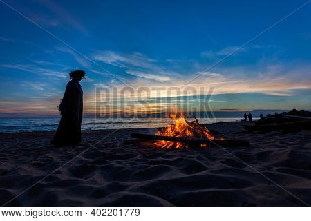 Unrecognisable people celebrating summer solstice with bonfires on beach