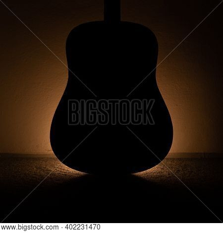 Photo Of Silhouette Of An Acoustic Wooden Guitar Lighting From Behind With A Candle.