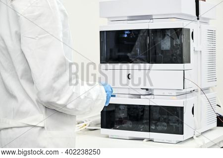 Scientist In Rubber Gloves And White Lab Coat Standing Near High Performance Liquid Chromatography H