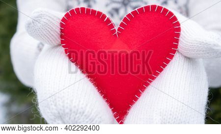 Red Heart Close Up As A Concept Of Declaration Of Love For Valentine's Day. A Woman In White Woolen 