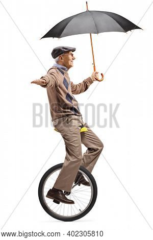 Full length profile shot of an elderly man riding a mono-cycle and holding an umbrella isolated on white background