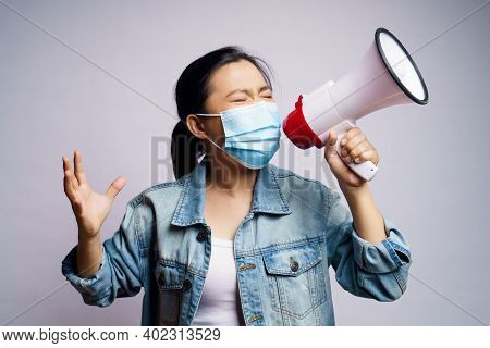 Asian Woman Wearing Protective Face Mask Shouting With Megaphone Isolated Over White Background.