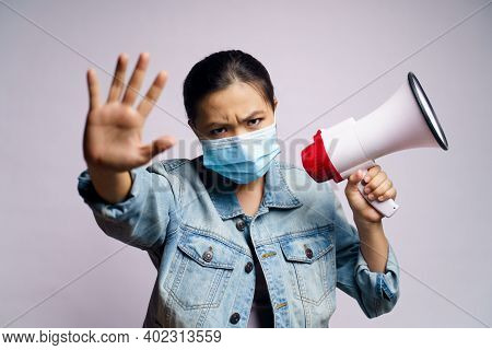 Asian Woman Wearing Protective Face Mask Shouting With Megaphone Isolated Over White Background.