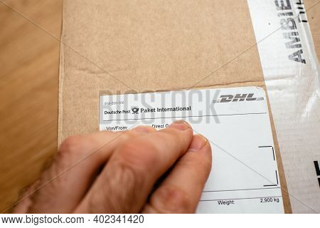 Paris, France - Dec 15, 2020: Pov Male Hand Holding On The Front Of Dhl Deutsche Post Paket Internat