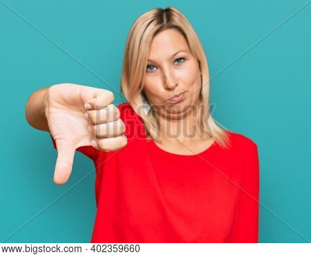Middle age caucasian woman wearing casual clothes looking unhappy and angry showing rejection and negative with thumbs down gesture. bad expression. 