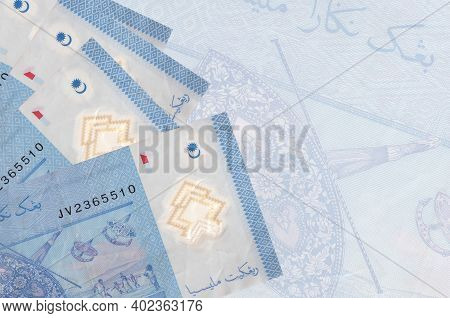 1 Malaysian Ringgit Bills Lies In Stack On Background Of Big Semi-transparent Banknote. Abstract Bus