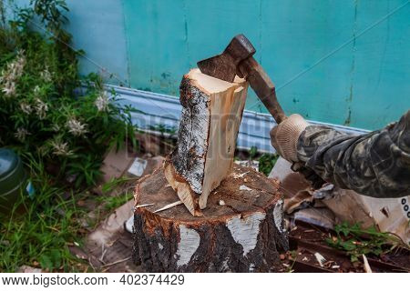A Log Split In Half With An Ax On A Deck With Male Hands In Cloth Gloves And A Camouflage Jacket In 