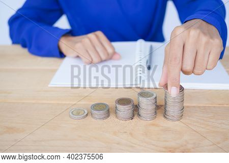 Close Up Woman Holding Coin With Stack Cash And Book, Pen On Wood Background. Future Finance. Saving