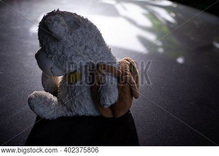 Broken Heart Concept. Alone Teddy Bear Sitting On Black Dark Floor. Conveys A Lonely Mood, Chagrin, 