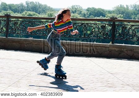 Cheerful Beautiful Teenage Girl Rollerblading In The Park On Awarm Summer Morning