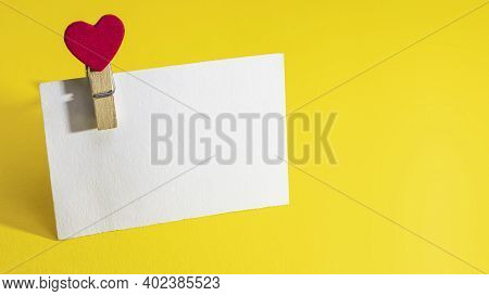 White Paper Plaque With Place For Text With Heart-shaped Clothespin. Bright Yellow Background. Mock 