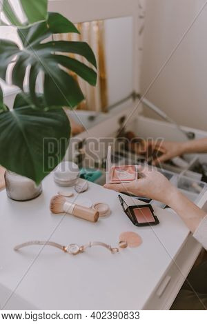 Young millennial woman is dressing up. Wearing earrings. Beauty routine. Make up artist. Mascara, li