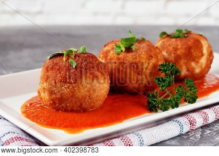 Delicious Hot Italian Arancini - Rice Balls Stuffed With Cheese In Tomato Sauce, In A Plate On An Ol