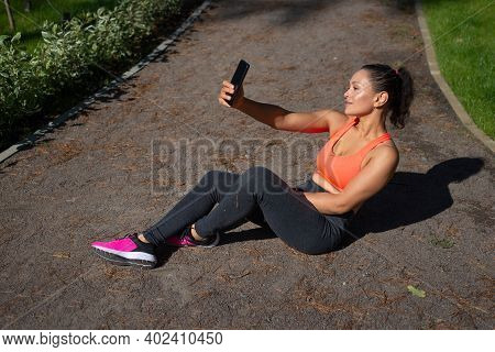 Cute Sporty Woman Having Rest And Making Selfie Afer Exercising In The City Park