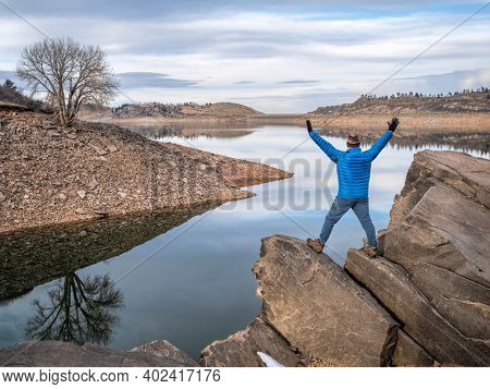 happy male hiker on a rocky shore of a mountain lake at foothills of Rocky Mountains, Horsetooth Reservoir - a popular recreational area in northern Colorado in falll or winter scenery
