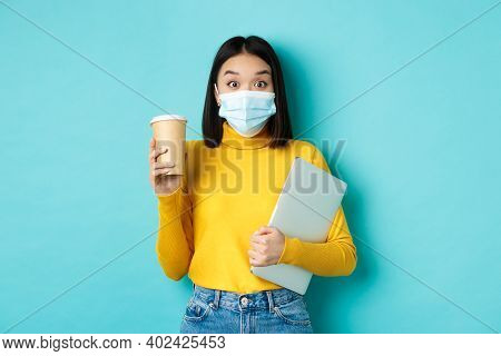 Covid-19, Health Care And Quarantine Concept. Asian Girl Student In Medical Mask Standing With Lapto