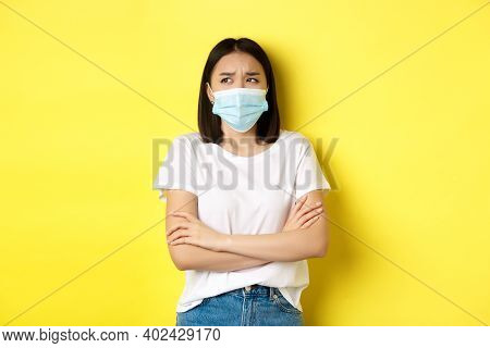 Covid, Health Care And Pandemic Concept. Asian Woman In White T-shirt And Medical Mask Cross Arms On
