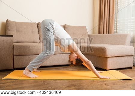 Beautiful Young Pregnant Woman Sitting Near Sofa In Yoga Pose At The Home. Pregnancy Yoga And Fitnes